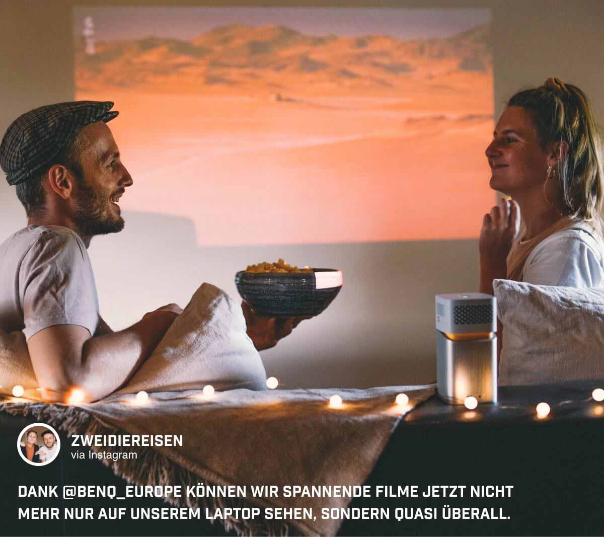 @zweidiereisen sitzen gemeinsam vor der Leinwand und spielen ihre Lieblingsinhalte auf dem Minibeamer GV1 ab